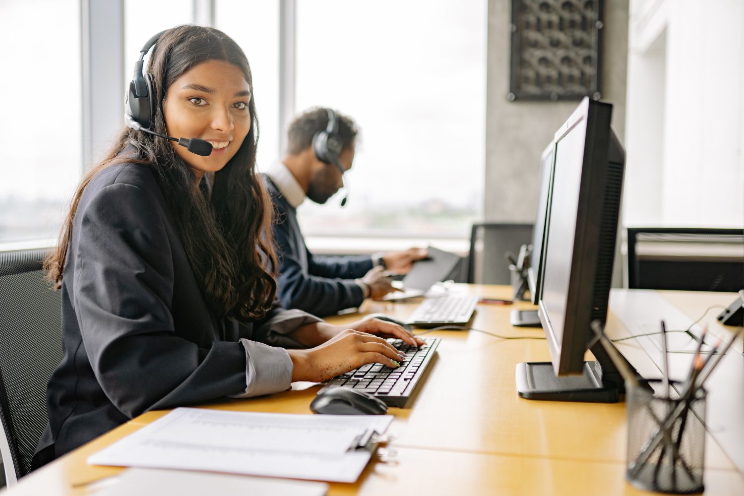 Smiling outbound agent with a headset working at a computer